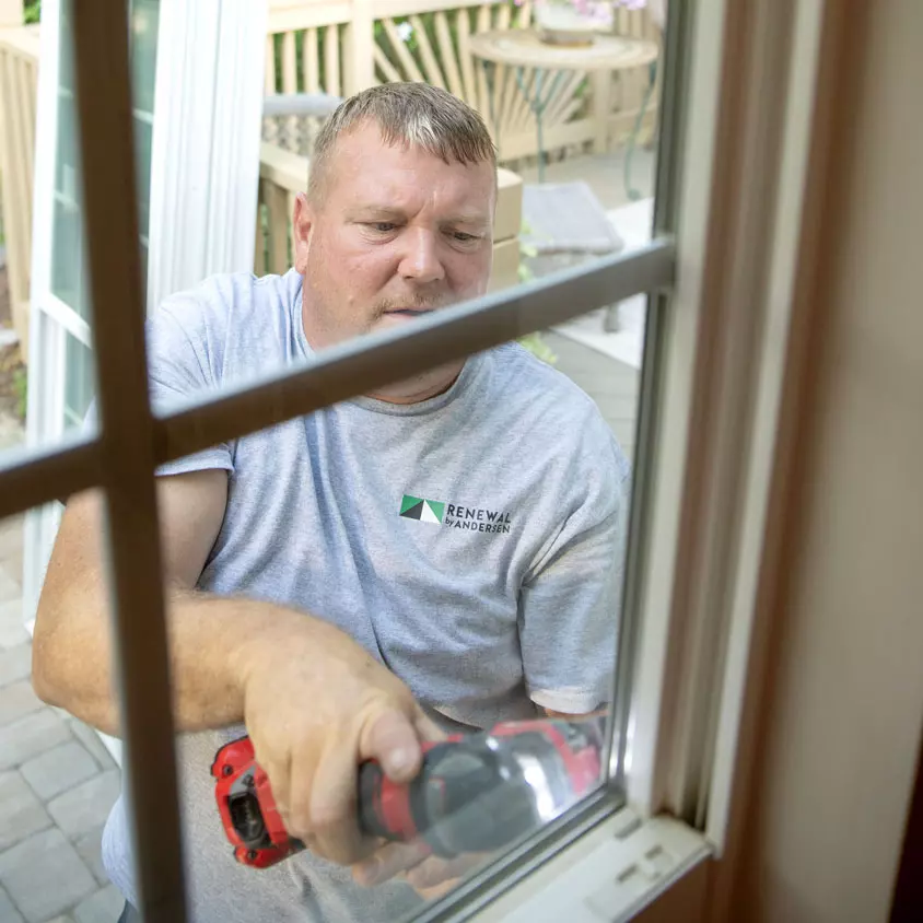 A Renewal by Andersen crew member uses a power tool to remove an old window.